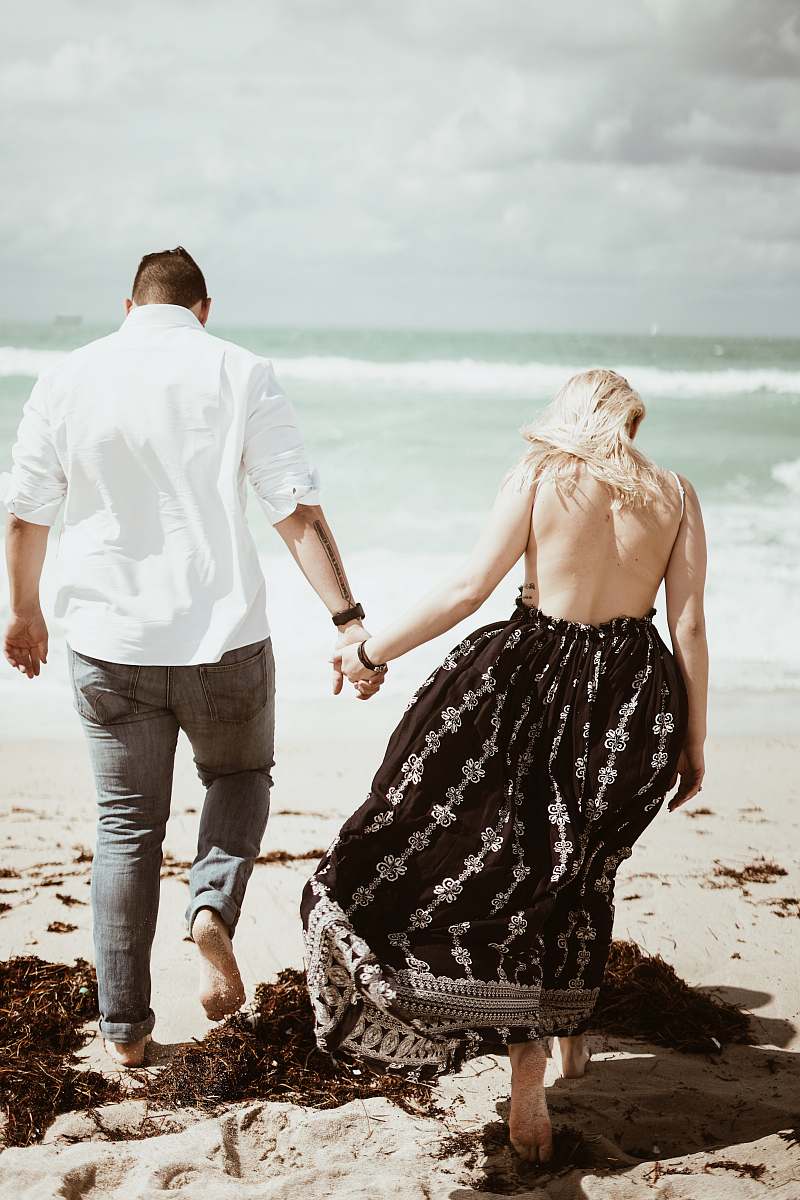 holding hands couple walking on sand near beach during daytime human